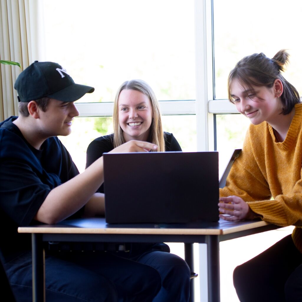 Tre elever fra Campus Odsherred sidder ved et bord med en computer foran sig.